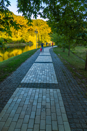Paved multi-colored tile walking alley on the shore of a large transparent decorative lakeの写真素材