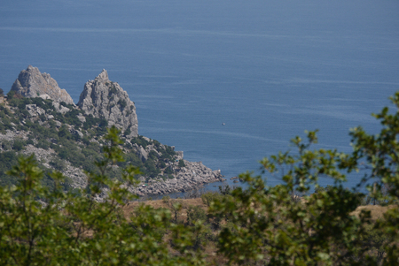 The only ship floating along the blue sea waves near the rocky mountainsの写真素材