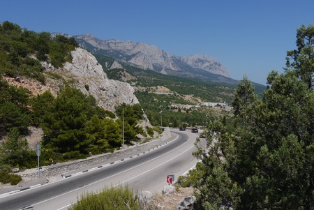 the road is twisted in the middle of the great mountains covered with trees on the background of a blue skyの写真素材