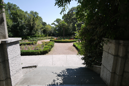Stone steps leading to a small decorative square with a round flower bed in the middleの写真素材