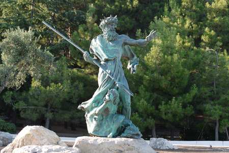Sculpture of Neptune with a spear on a stone in the background of a coniferous parkのeditorial素材