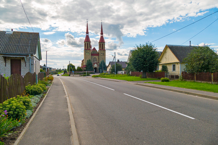 small houses on the background of a tall church with a red roofのeditorial素材
