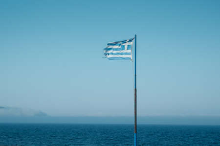 Greek flag waving in a wind over turqoise shore seascape in the summerの写真素材