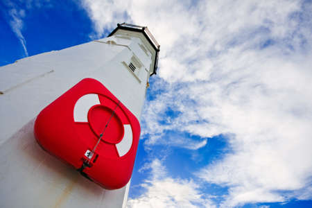 White lighthouse with a red life preserver against a cloudy blue sky on a bright winter morning. Photo taken in Anstruther, Scotland.の写真素材