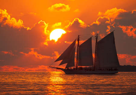 A boat sailing in front of a beautiful sunset in Key West, Florida.の写真素材