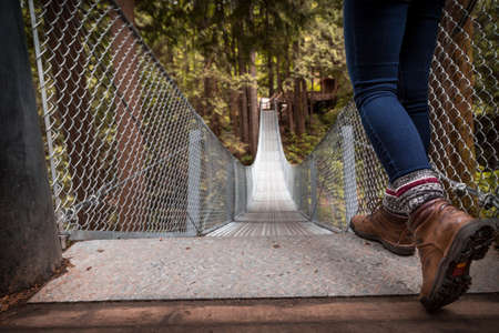 Hiking boots at the top of a suspension bridge in a forest.