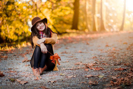 Girl in a park with autumn leaves around her.の写真素材