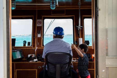 ISLA MUJERES, QR, MEXICO - FEB 11, 2018: Young boy queries a ferry captain who is piloting a ferry...