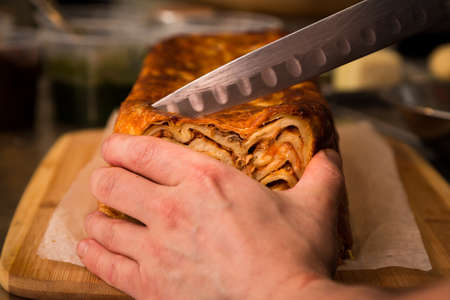 Close-up of timballo being cut with a chefs knife.