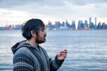 A young man smoking a joint with downtown Vancouver, BC, in the background shortly after Canadian marijuana legalization.の写真素材