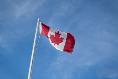 Waving Canadian flag against the blue sky.