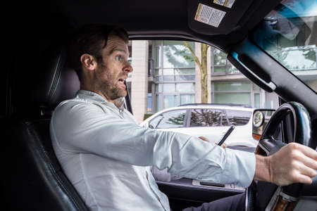 A middle aged caucasian man distracted driving while using a mobile device stops his vehicle...