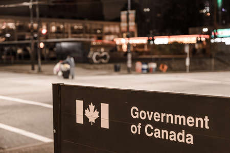 VANCOUVER, BC, CANADA - OCT 05, 2019: A homeless man with a shopping cart passing by a Government of Canada federal bulding in downtown Vancouverのeditorial素材