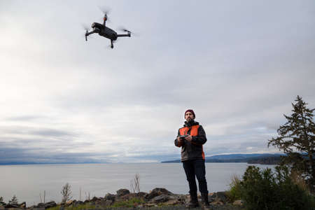 A professional drone pilot flying a drone near the ocean.