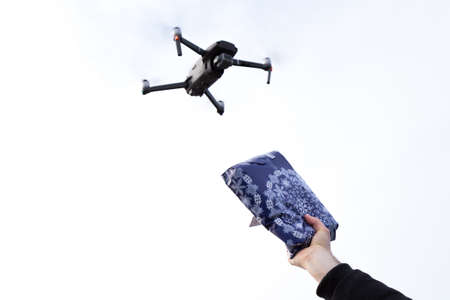 An autonomous mail delivery drone with a hand holding up a package to the sky.の写真素材
