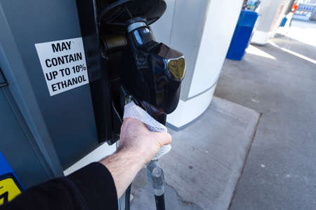 A mans hand with a disinfecting wipe in it holding a gas pump as a precaution during the Coronavirus pandemic 2020.の写真素材