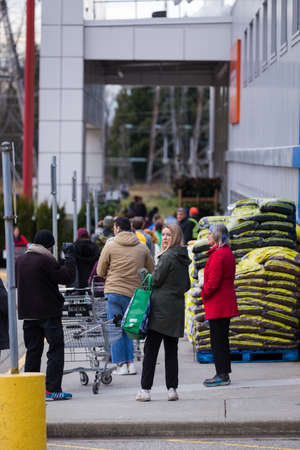NORTH VANCOUVER, BC, CANADA - MAR 23, 2020: Shoppers at a local supermarket waiting in line to stock up on groceries in anticipation of supply shortages over the coming weeks as the Coronavirus pandemic worstens.のeditorial素材
