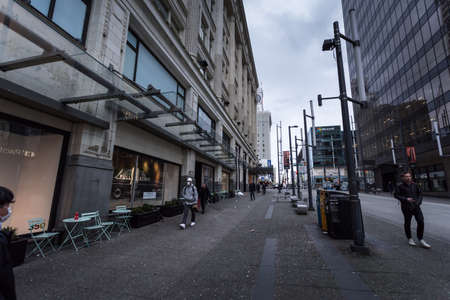 DOWNTOWN VANCOUVER, BC, CANADA - MAR 23, 2020: Pedestrians walking around mostly empty downtown Vancouver streets with medical face masks on to protect against the COVID-19 virus.のeditorial素材