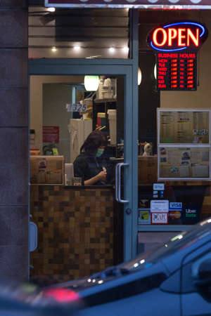 DOWNTOWN VANCOUVER, BC, CANADA - MAR 23, 2020: A worker at a downtown business wearing a facemask during the COVID-19 virus pandemic.のeditorial素材