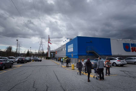 NORTH VANCOUVER, BC, CANADA - MAR 23, 2020: Shoppers at a local supermarket waiting in line to stock up on groceries in anticipation of supply shortages over the coming weeks as the Coronavirus pandemic worstens.のeditorial素材