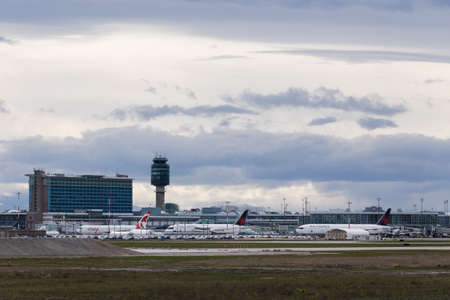 RICHMOND, BC, CANADA - MAR 29, 2020: Air Canada aircraft parked on the tarmac with YVR airport in the background during a global reduction in air travel due to the COVID-19 coronavirus pandemic.のeditorial素材
