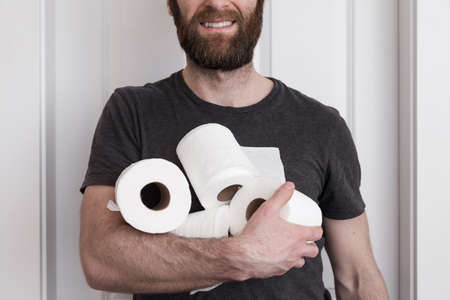 A smiling caucasion man holding rolls of toilet paper the he hoarded.の写真素材