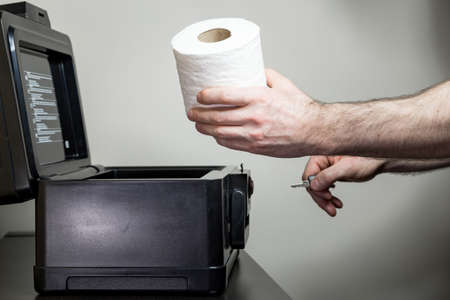 Covid 19 concept of a man taking a roll of toilet paper out of a lockbox that he was hoarding.の写真素材