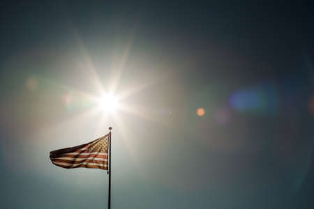 A simple composition of an American flag flying backlit with a sunburst