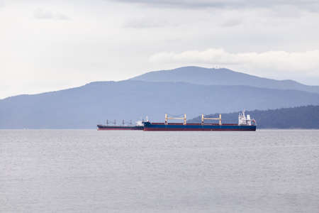 Cargo and tanker ships moored in Vancouver harbor awaiting to be loaded.