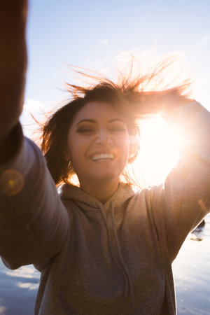 Young woman with cell phone, sunset beach, waves crashingの写真素材