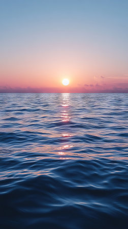 A beautiful sunset over the ocean, with the sun reflecting off the water.の素材
