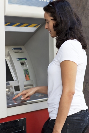 Good-looking latin woman enters the PIN number at the ATMの写真素材