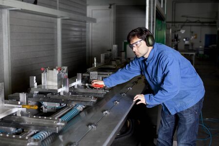 Blue collar worker at machine in factory