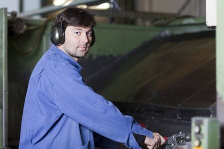 Blue collar worker at machine in factory