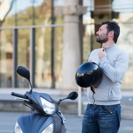 man with scooter takes off helmetの写真素材