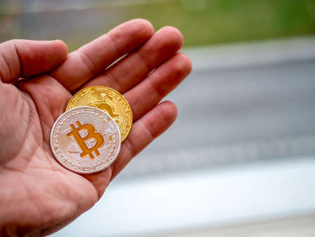 Bitcoins in silver and gold in a hand. Crypto currency concept with bokeh background.の写真素材