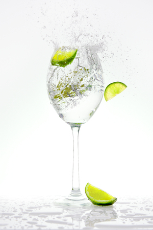 Fresh lime falling into a splashing sparkling water.の写真素材