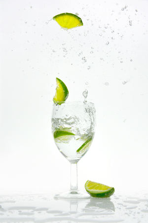 Slice of lime pops from a glass with sparkling waterの写真素材