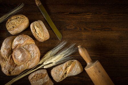 Traditional fresh bread with a blade of wheat on a wooden background. 
Buns and ears of cerealの写真素材