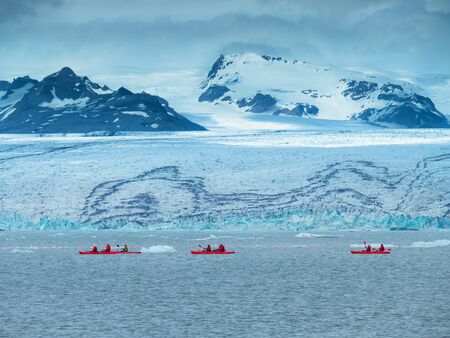 A group of tourists in red kayaks near the JÃ¶kulsÃ¡rlÃ³n glacier lagoon. South Icelandの写真素材