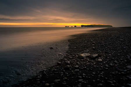 Sunset over the Dyrholaey peninsula as seen from the black beach of Reynisfjara. South Iceland....