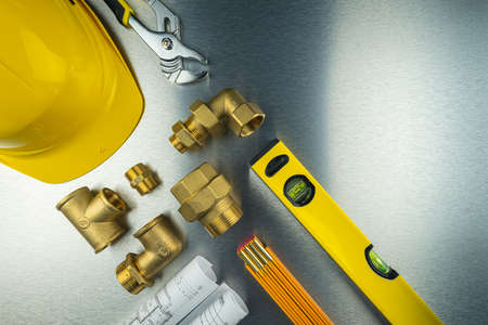 Flat lay composition with plumber's tools on brushed aluminum
