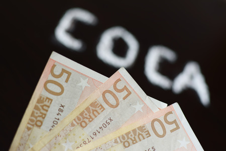 Banknote and text COCA blurred  written with cocaine power