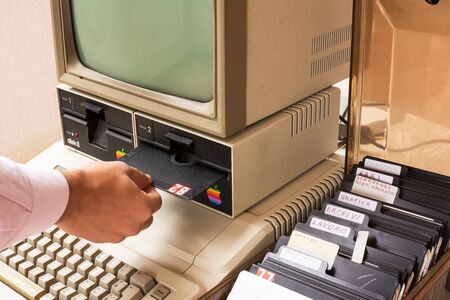 Aged Apple computer and hand insert floppy insideのeditorial素材