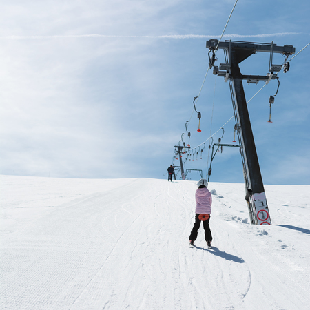 Beginner little girl with skis ascends with ski liftの写真素材