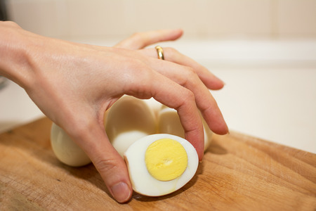 Hard-boiled egg cut in half held between the fingersの写真素材