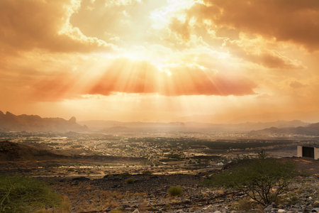 Cloudy sky slashed by the sun's rays over the village of Al Hamra (Oman)の写真素材