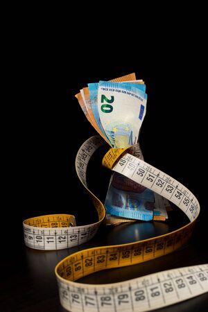 Banknotes tightened by the tape measure on a black background for the concept of financial crisisの写真素材