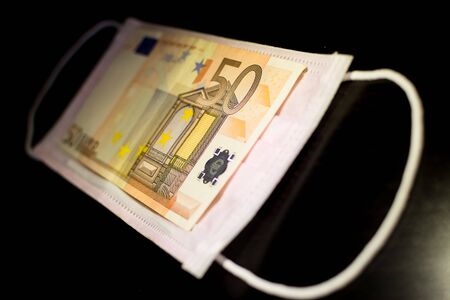 Medical face masks and money. Surgical face mask. COVID-19 Has Caused A Shortage Of Face Masks. Euro banknotes and Medical face masksの写真素材