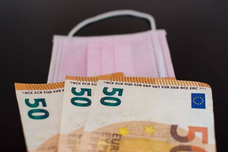 Medical face masks and money. Surgical face mask. COVID-19 Has Caused A Shortage Of Face Masks. Euro...
